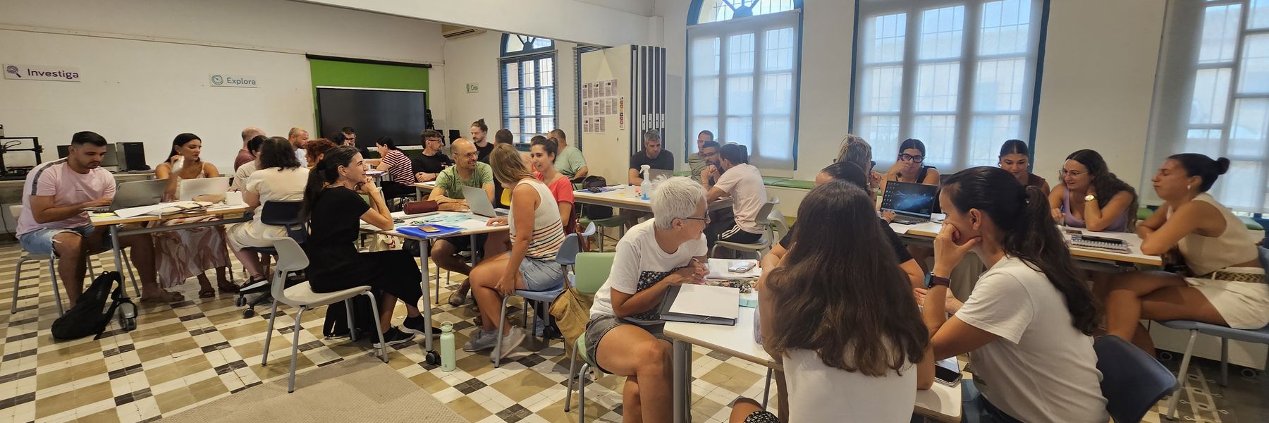 Sessió de formació amb un grup nombrós de docents treballant en equips en una aula